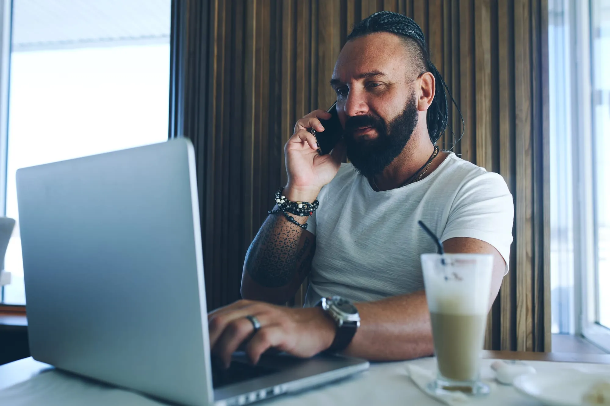 Mobile mechanic taking a customer call while reviewing jobs on a laptop